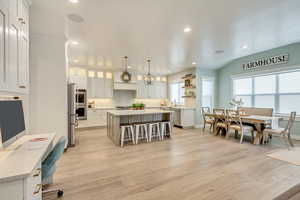 Kitchen with a kitchen island, white cabinetry, light countertops, open shelves, and pendant lighting