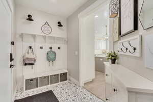 Mudroom featuring light tile patterned flooring, baseboards, and an inviting chandelier