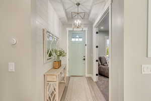 Foyer entrance featuring light wood-style floors, baseboards, and a chandelier