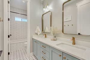 Bathroom featuring a sink, tiled shower / bath combo, toilet, and double vanity