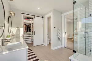 Full bathroom with a walk in closet, double vanity, recessed lighting, a stall shower, and a sink