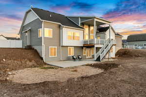 Back of house with central air condition unit, stairway, board and batten siding, a patio area, and fence