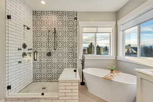 Full bath with a freestanding bath, a wealth of natural light, a shower stall, and vanity