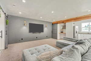 Cinema with light carpet, a barn door, visible vents, wood walls, and recessed lighting