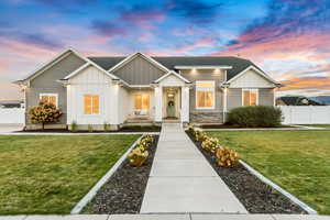 View of front facade with board and batten siding, a front yard, and fence