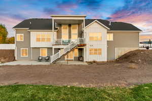 Rear view of house with stairway, board and batten siding, and a patio