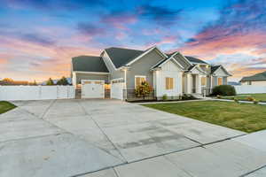 View of front facade with a garage, fence, concrete driveway, board and batten siding, and a front yard