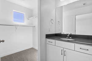 Bathroom featuring visible vents, baseboards, a spacious closet, and vanity