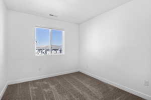 Spare room featuring carpet flooring, visible vents, and baseboards