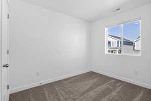 Carpeted spare room with visible vents and baseboards