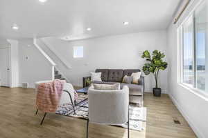 Living room featuring light wood-style floors, visible vents, and baseboards