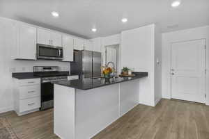 Kitchen with dark countertops, stainless steel appliances, a peninsula, and a sink