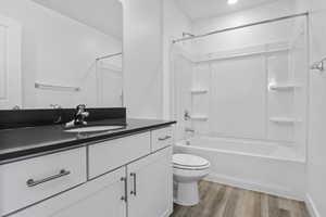 Full bath with toilet, washtub / shower combination, wood finished floors, and vanity