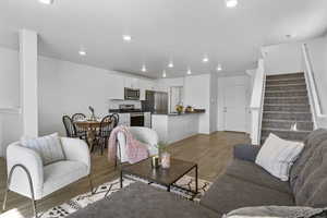 Living room with light wood-type flooring, stairway, a textured ceiling, and recessed lighting