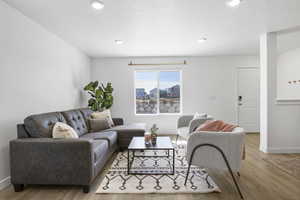 Living area featuring light wood-type flooring, a textured ceiling, and baseboards