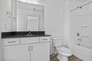 Full bathroom featuring washtub / shower combination, vanity, toilet, and wood finished floors