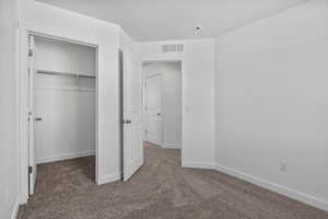 Unfurnished bedroom featuring carpet floors, a closet, visible vents, and baseboards