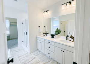 Full bathroom with double vanity, marble finish floor, a sink, and a stall shower