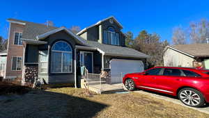 Traditional-style house with a garage, a shingled roof, and stucco siding