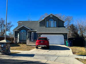 Traditional home with a garage, concrete driveway, and a shingled roof
