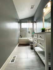 Bathroom with shower / bathtub combination, vaulted ceiling, vanity, and visible vents
