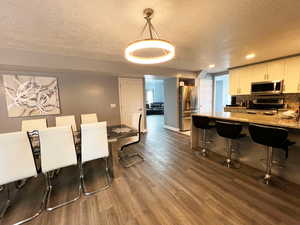 Dining room featuring recessed lighting, a textured ceiling, baseboards, and wood finished floors