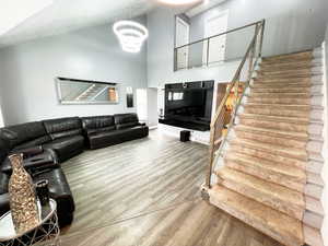 Living area with baseboards, stairway, wood finished floors, a high ceiling, and a chandelier