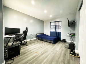 Bedroom with a textured ceiling, baseboards, and light wood-style floors
