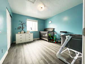 Bedroom with a textured ceiling, a closet, light wood-style flooring, and baseboards