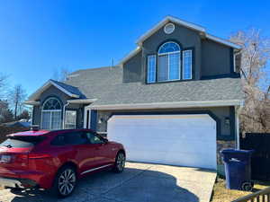 Traditional home with driveway, a shingled roof, stone siding, and stucco siding