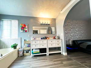 Full bathroom featuring a garden tub, a textured ceiling, wood finished floors, and vanity
