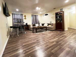Living room featuring a bar, dark wood finished floors, and baseboards