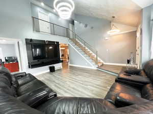 Living area featuring baseboards, visible vents, stairway, wood finished floors, and a textured ceiling