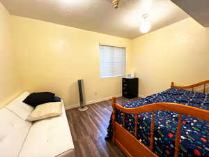 Bedroom with dark wood-type flooring, a textured wall, a textured ceiling, and baseboards