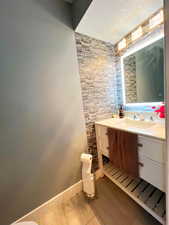 Half bathroom with baseboards, toilet, wood finished floors, a textured ceiling, and vanity