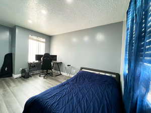 Bedroom with a textured ceiling, wood finished floors, and baseboards