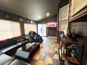 Living area featuring lofted ceiling, stone tile floors, and recessed lighting