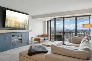 Living area featuring a textured ceiling, carpet, and a tile fireplace