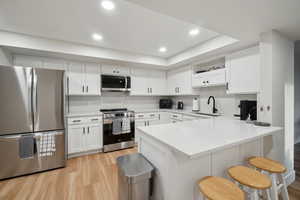 Kitchen featuring a sink, appliances with stainless steel finishes, white cabinets, and light countertops