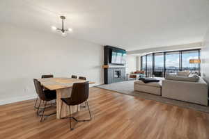 Dining area with light wood-type flooring, a fireplace, baseboards, and an inviting chandelier