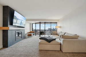 Living area with a wall of windows, carpet flooring, a fireplace, and a textured ceiling