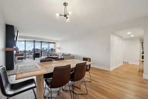 Dining area with light wood-style floors, baseboards, visible vents, and an inviting chandelier