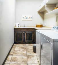 Clothes washing area with cabinet space, a sink, and independent washer and dryer