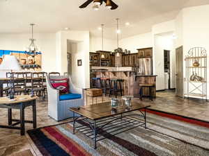 Living room featuring lofted ceiling, tile patterned flooring, and ceiling fan with notable chandelier