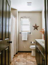 Bathroom featuring visible vents, toilet, vanity, baseboards, and tile patterned floors