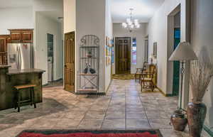 Entrance foyer featuring tile patterned flooring, a notable chandelier, a towering ceiling, baseboards, and washer / dryer