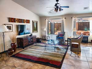 Living area with lofted ceiling, a wood stove, visible vents, and a textured ceiling