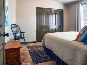 Bedroom featuring light tile patterned floors, a closet, and baseboards