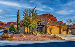 View of front facade with a garage, concrete driveway, a tile roof, a mountain view, and stucco siding