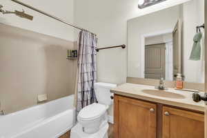 Bathroom with toilet, shower / bath combo with shower curtain, and vanity